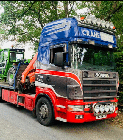 Red and blue Hiab carrying a green tractor